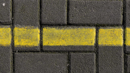 Gray paving block bricks. There is a yellow line in the middle
