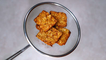Tempe or tempeh after frying put in colander. Focus selectedの写真素材