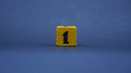 Wooden block with number 1. Yellow color on dark backgroundの写真素材