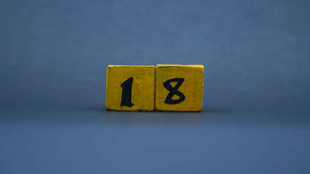 Wooden block with number 18. Yellow color on dark backgroundの写真素材