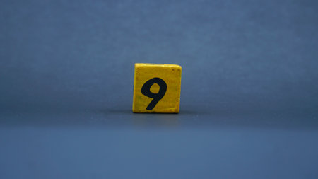 Wooden block with number 9. Yellow color on dark backgroundの写真素材