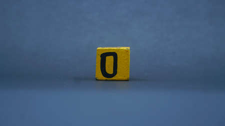 Wooden block with number 0. Yellow color on dark backgroundの写真素材