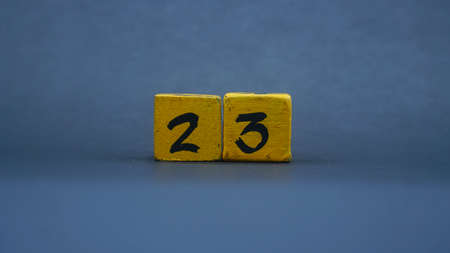 Wooden block with number 23. Yellow color on dark backgroundの写真素材