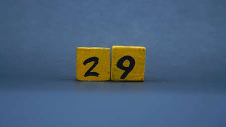 Wooden block with number 29. Yellow color on dark backgroundの写真素材