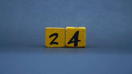 Wooden block with number 24. Yellow color on dark backgroundの写真素材