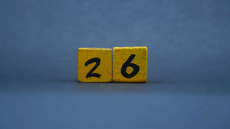 Wooden block with number 26. Yellow color on dark backgroundの写真素材