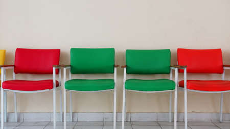 Rows of empty red and green chairs. Plain wall backgroundの写真素材