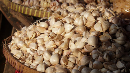 Pile of garlic on a bamboo basket exposed to the morning sun at a traditional market. Focus is selectedの写真素材