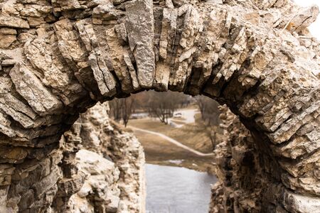 A fragment of a stone arch from limestone. Ruins of a medieval Russian fortress. Remains of the entrance to the tower.の写真素材