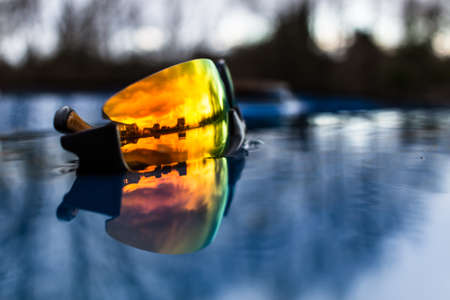 Yellow modern sunglasses in the water with houses reflecting in it.の写真素材
