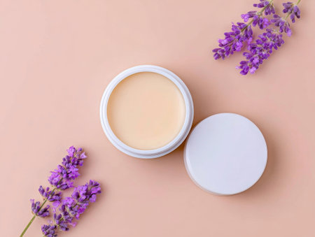 Cream jar opened on soft peach backdrop. Decorated with lavender and herbs, this skincare item exudes relaxation. Great for spa or wellness imageryの素材