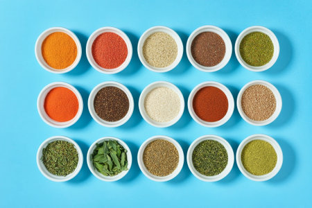 Spices and herbs in bowls on a blue background, top viewの素材