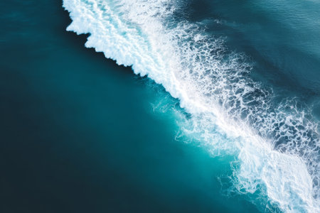 Top view ocean waves turquoise coast. Blue waves hit sandy shore from above, perfect for marine landscape photos.の素材