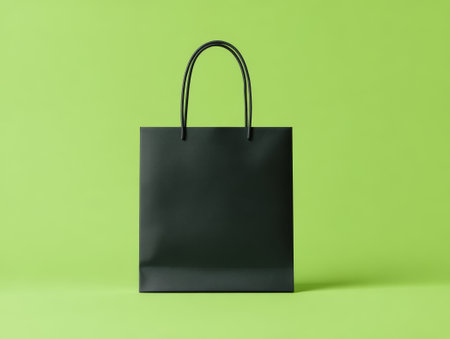 Black kraft bag with black accents on green backdrop. Modern vibe for shopping or sustainability themes, perfect for sleek or eco-friendly designs. Ideal for packaging or stylish visuals.の素材