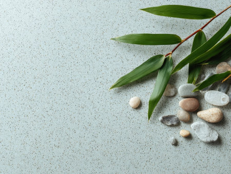 Bamboo leaves with stones on soft textured background, offering a zen feel. Natural setup brings calm and serene vibes.の素材