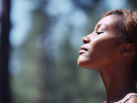 Girl enjoying deep breath in natural forest with green leaves and gentle glow. Health and tranquility shown in peaceful outdoor moment.の素材