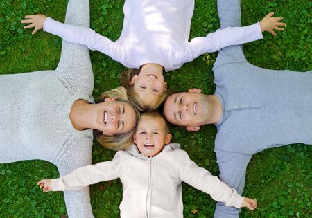 Family lying on the grass and smiling top viewの写真素材