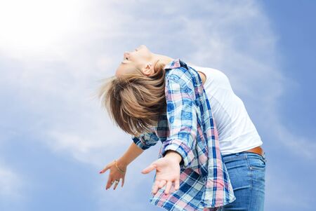 Free girl enjoying life. beautiful woman smiling against the blue summer skyの写真素材