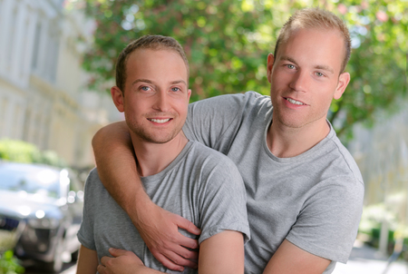 Two  guys on a street. Portrait how they huggingの写真素材