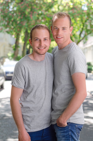 Two  men standing on a street at at sunny day, happy smiling and huggingの写真素材