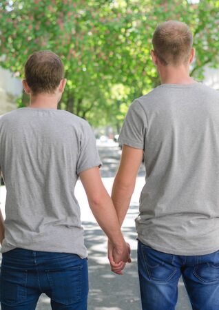 Two  male hold hands and looking on the street. Backsideの写真素材