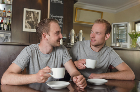 two young gay couple drinking coffee in cafe bistroの写真素材