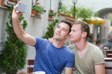 Shot of a young gay couple taking a selfie in a favorit cafeの写真素材