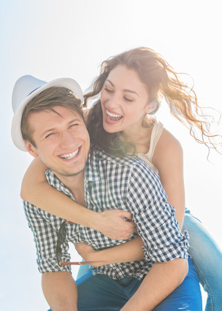 happy young man giving his girlfriend a piggyback ride outdoorsの写真素材