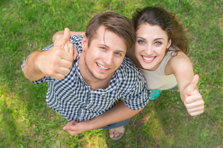young couple giving  thumbs up on grass background top viewの写真素材