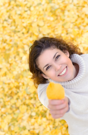 Top view portrait of a smiling woman showing autumn leaf with copyspaceの写真素材