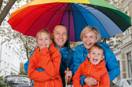 Happy rain family smile under colorful umbrellaの写真素材