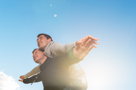 Homosexual couple giving piggyback ride, smiling outside. copyspace
の写真素材