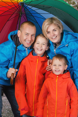 happy and colorful family under umbrella in rainy dayの写真素材