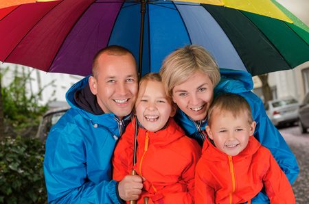 colorful family smiling in the rainy day under umbrellaの写真素材