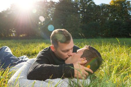 Shot of a kisses gay couple, lying at the grass の写真素材