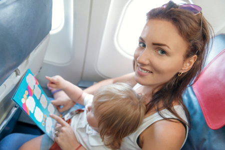Woman and baby girl checking  announcement in economy class airlinerの写真素材