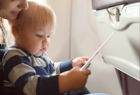 Woman and baby girl reading safety on board in economy class airlinerの写真素材