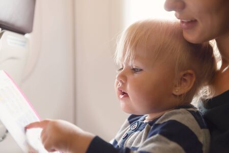 Close up shot of mother and her baby girl, read safety on board at  economy class airline. Copy space の写真素材