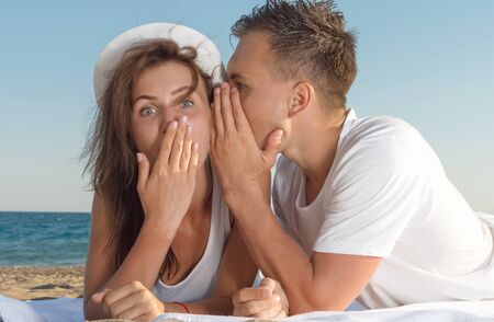 A young man whispering a secret in his girlfriend's earの写真素材