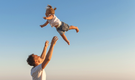 A Father swinging his  daughter  in the air against a sky background, Copyspace の写真素材