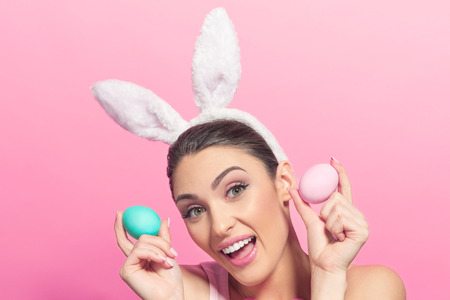 Studio shot of a excited young woman wearing bunny ears and holding a of Easter eggs on pink background
の写真素材