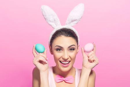 Studio shot of a excited young woman wearing bunny ears and holding a of Easter eggs on pink background
の写真素材