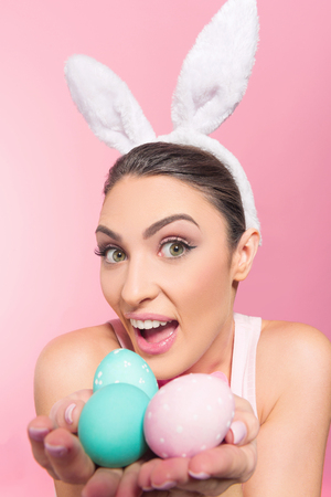 Happy  young woman wearing bunny ears and holding a handful of Easter eggsの写真素材