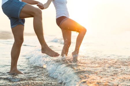 Cropped shot of a couple splashing in the water at the beachの写真素材