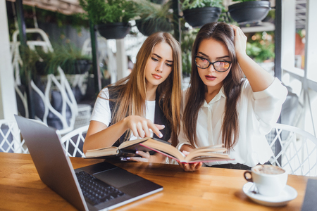 Teacher and young girl teaching new words in the caffe summer terraceの写真素材