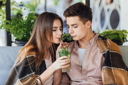 Boy and girl drink a cocktail on the summer terrace.の写真素材
