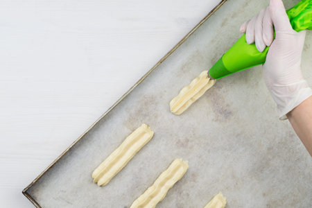 Forming eclairs from the dough using a pastry bag. Process of preparation of cakes.