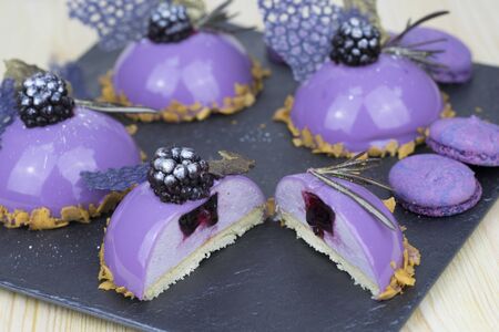 Glazed cakes with blueberries on a stone plate.の写真素材