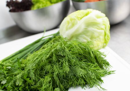 Greens and cabbage on a cutting board in the kitchenの写真素材