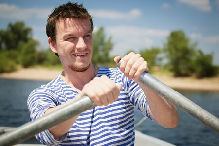 young man rows the boatの写真素材